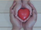 Two hands holding a heart icon.