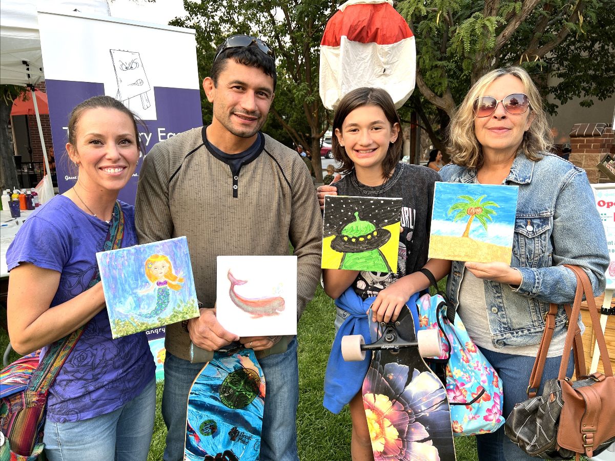 A group of residents holding up their paintings in a park