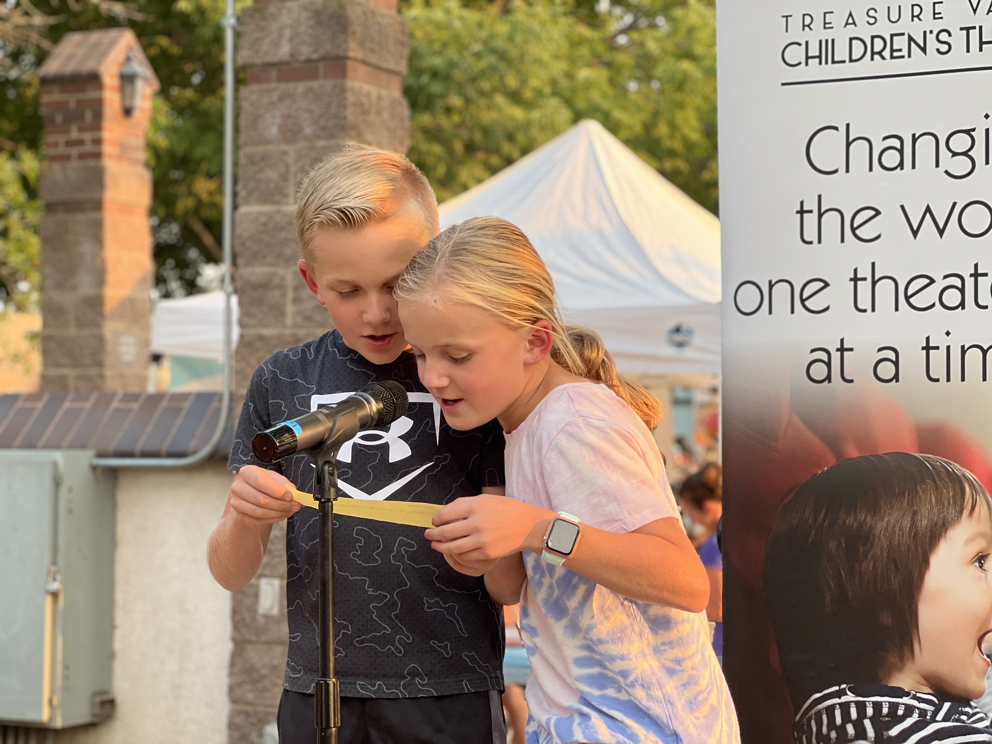 Youth on stage reading a prompt from Treasure Valley Children's Theater at the Art Party